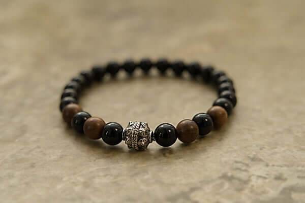 Black Onyx and Wood Bracelet with alternating black onyx and brown wood beads and a decorative silver bead centerpiece on a neutral background