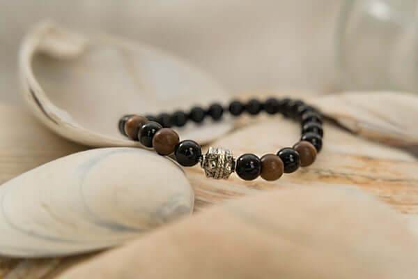 Black Onyx and Wood Bracelet with black onyx beads, brown wood beads, and silver accent bead on a natural background