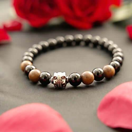 Black Onyx and Wood Bracelet with silver charm, handmade healing gemstone jewelry with fragrant Senna Siamewood beads, shown with rose petals background