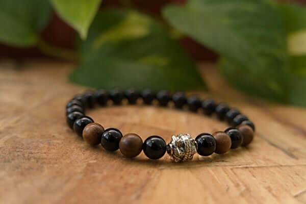 Black Onyx and Wood Bracelet with alternating black onyx and brown wood beads, featuring a silver decorative bead on wooden surface.