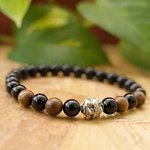 Black Onyx and Wood Bracelet with polished black onyx and fragrant Senna Siamewood beads, featuring a silver decorative charm.