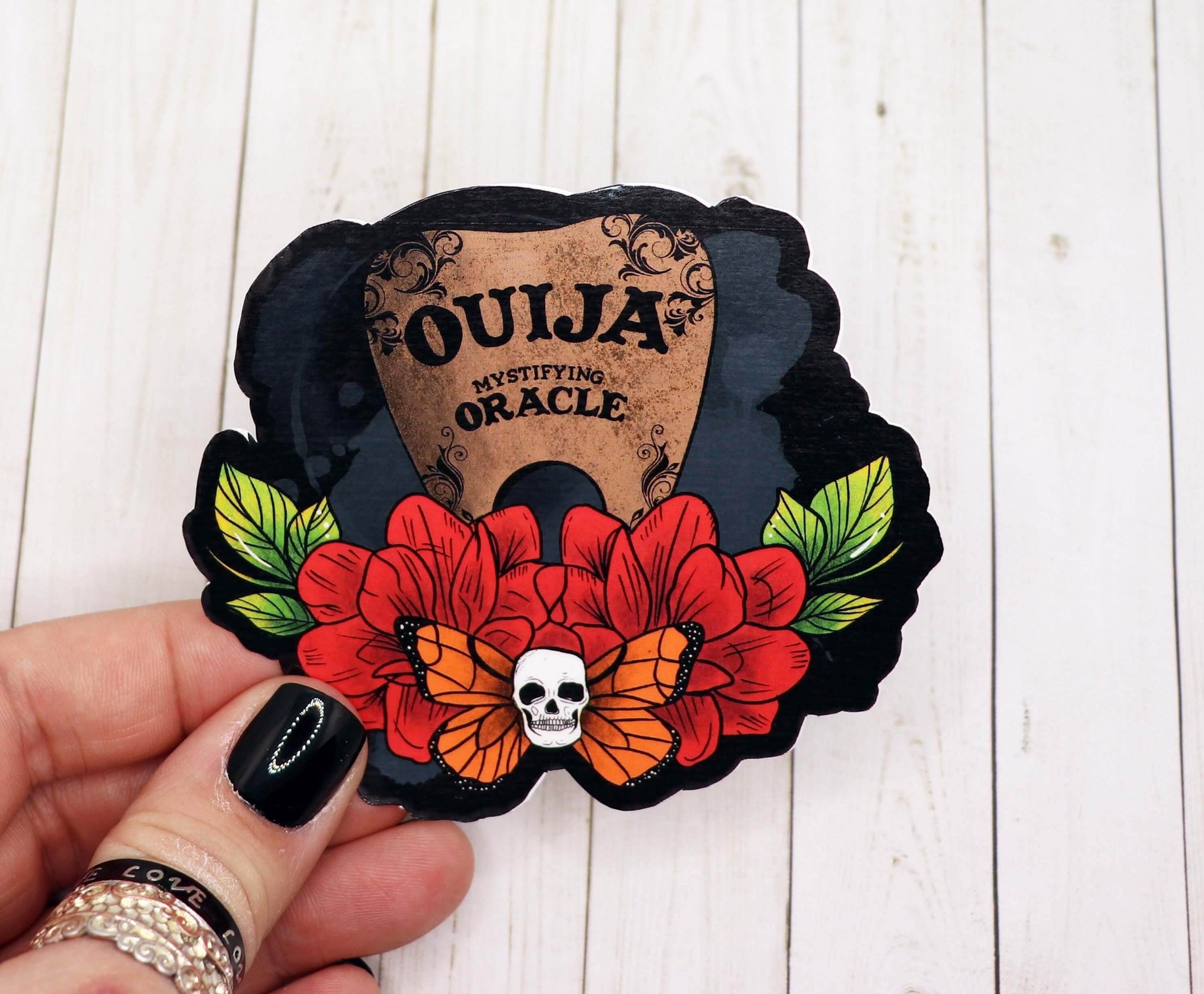 Ouija Board Planchette sticker with red flowers, skull, and butterfly design on matte vinyl paper