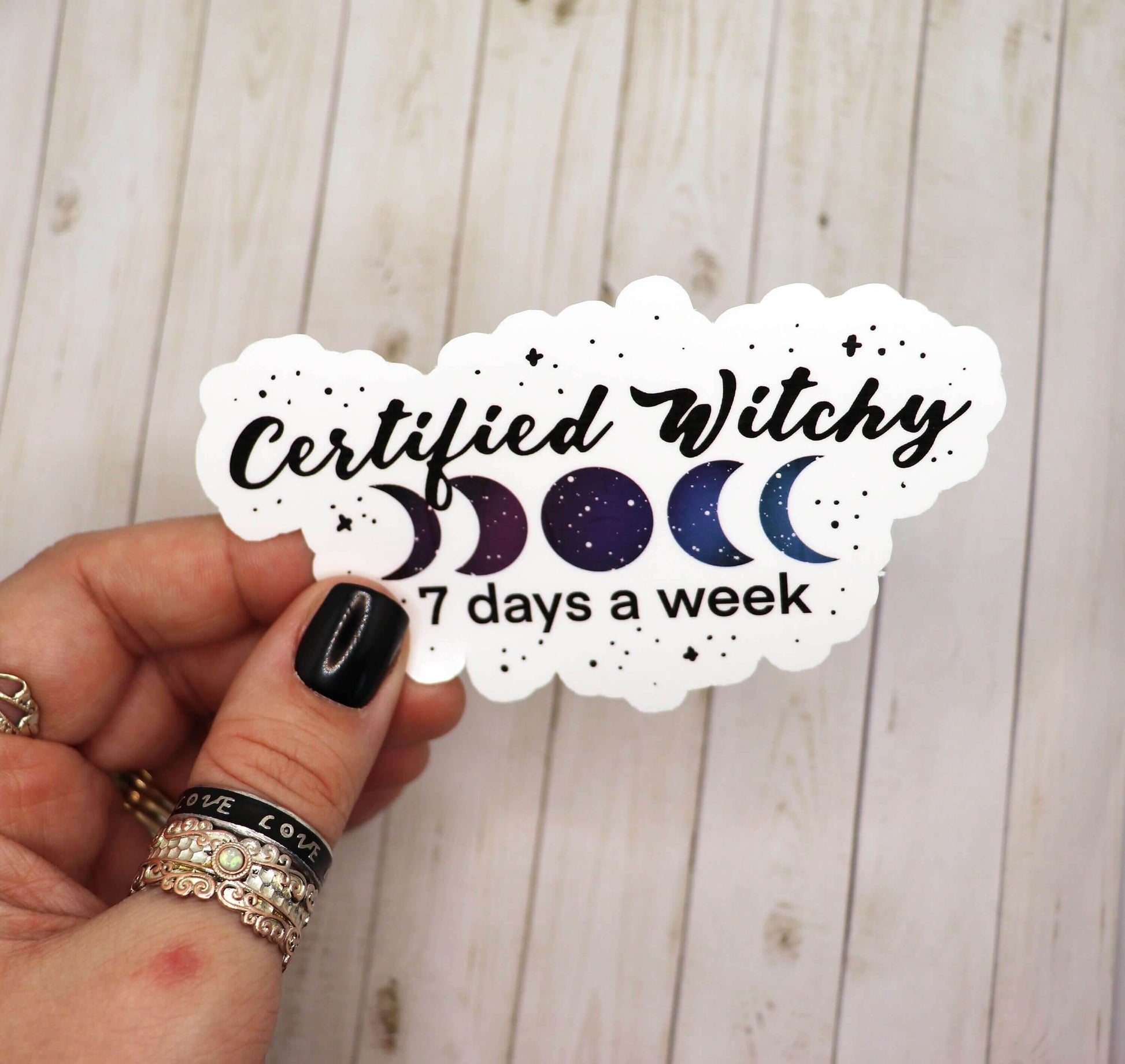 Hand holding Certified Witchy 7 Days a Week vinyl sticker with moon phases design on matte laminated vinyl paper