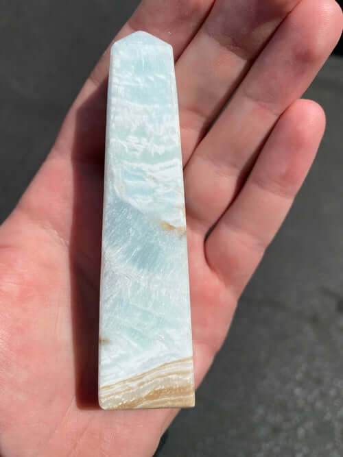 Caribbean Calcite Obelisk crystal with blue and beige hues held in hand for energy cleansing and healing.