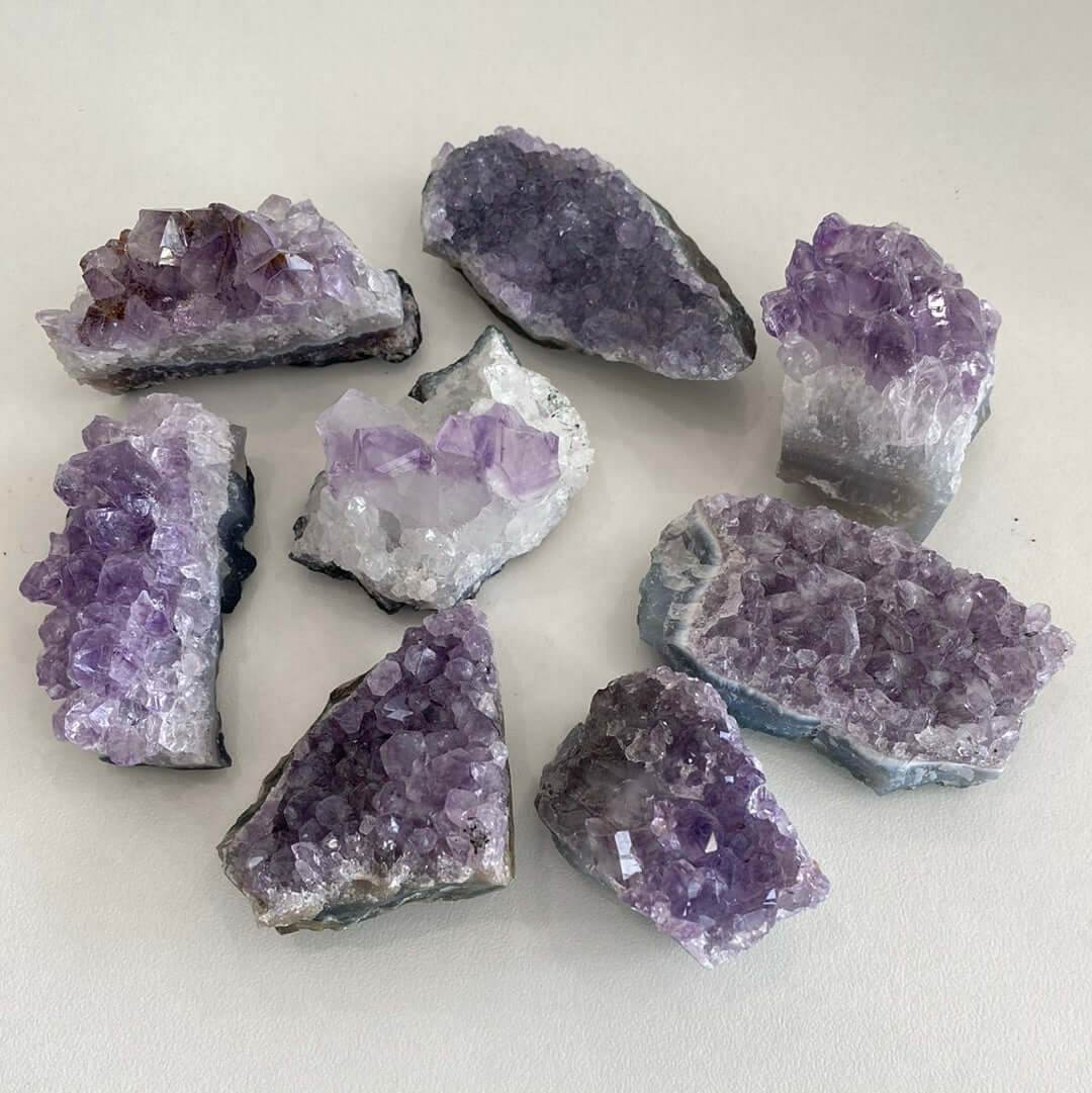 Small natural amethyst clusters with purple crystal formations on a light background